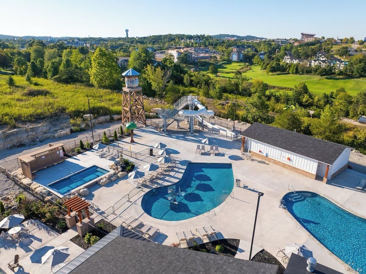 A swimming pool area with multiple pools, a water slide, and a tower structure.