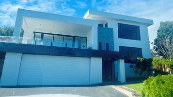 A modern two-story house with a garage, large windows, and a flat roof.