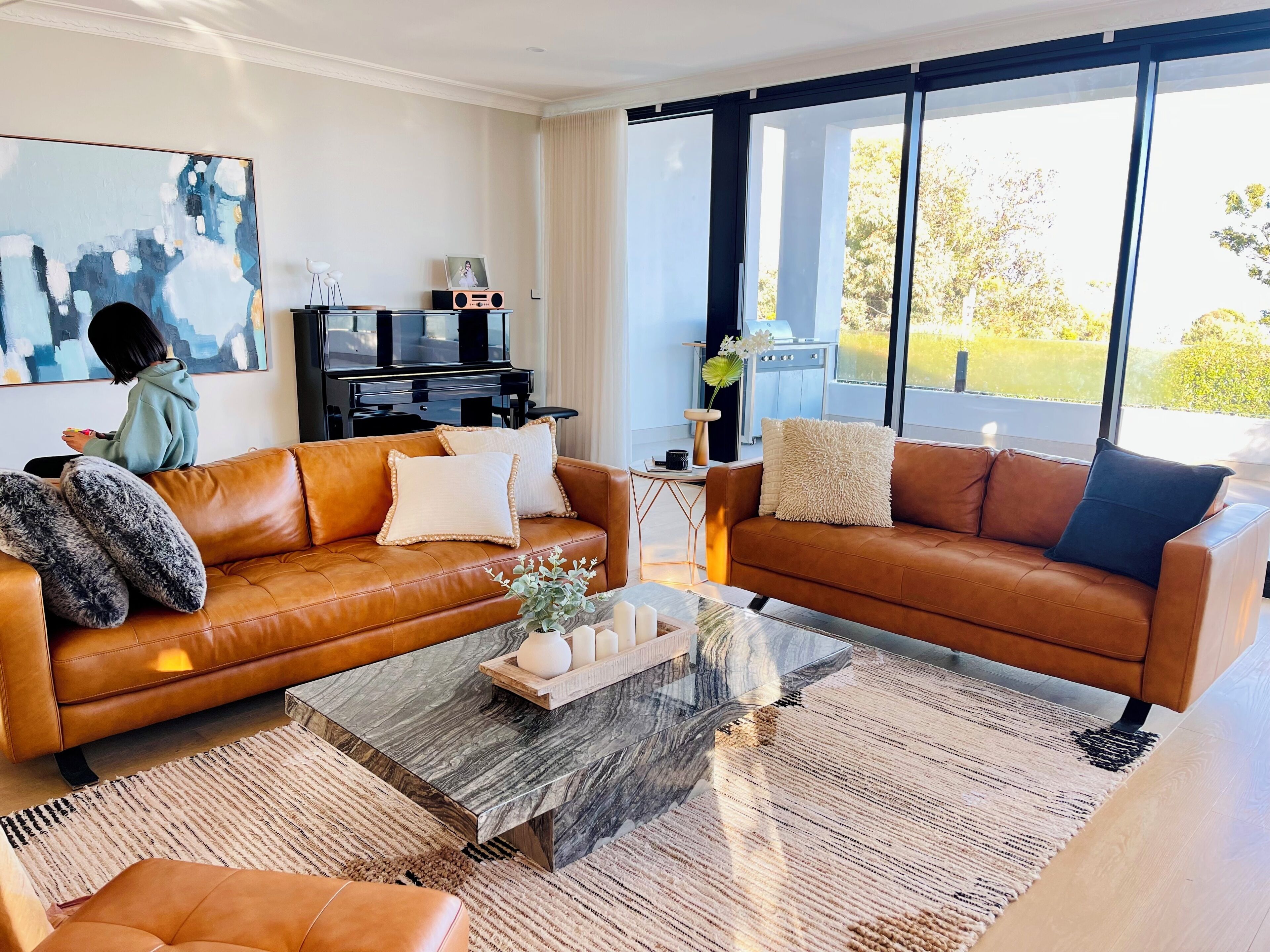 A modern living room with leather sofas, a coffee table, and a large window.