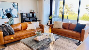 A modern living room with leather sofas, a coffee table, and a large window.