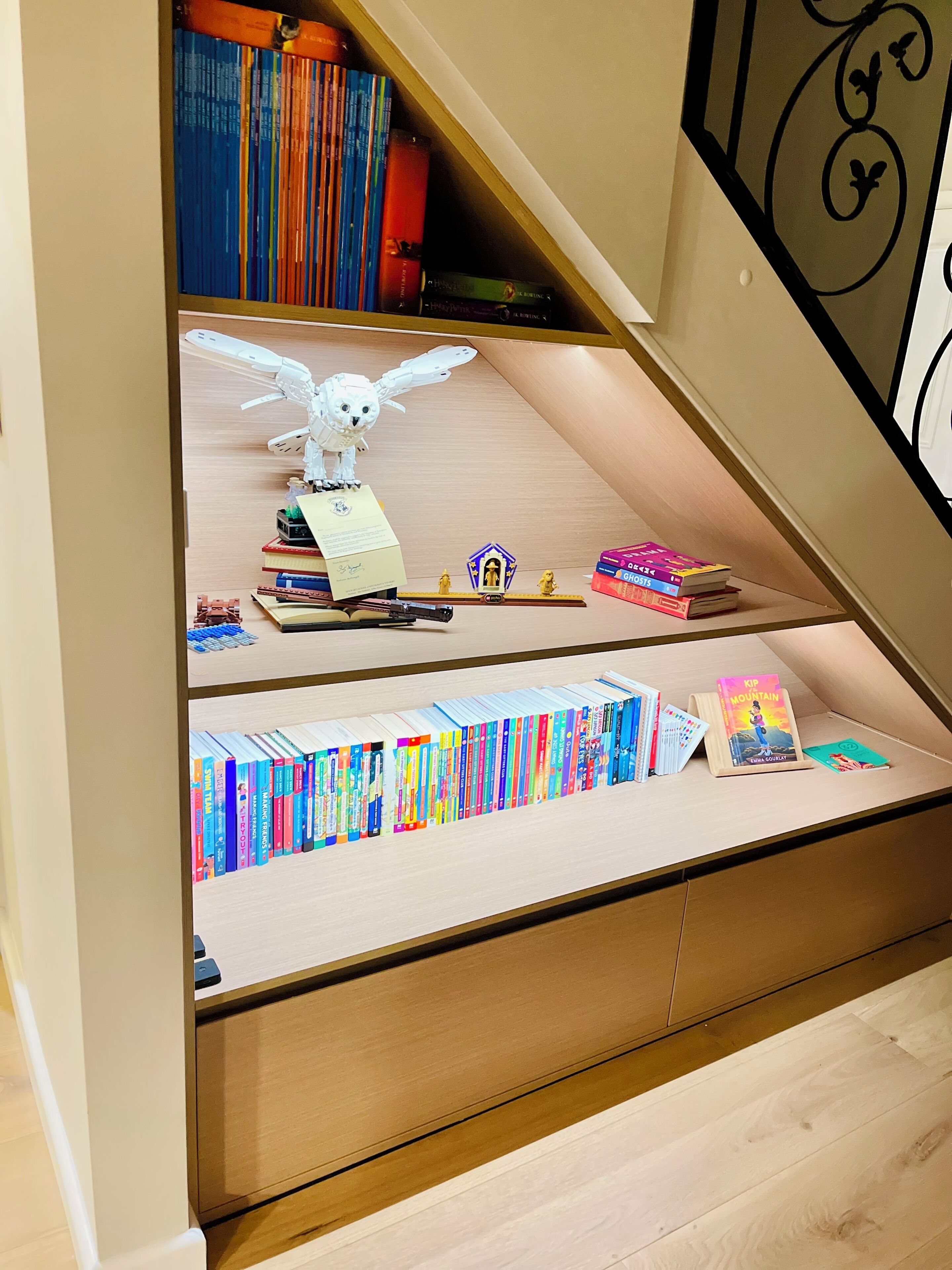 A bookshelf with various books and a small figurine.