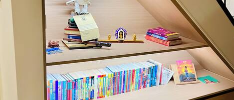 A bookshelf with various books and a small figurine.