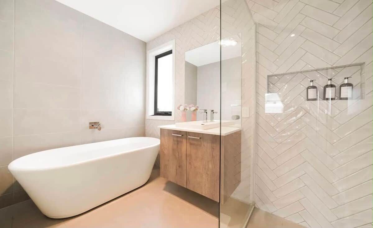 Une salle de bain moderne avec une baignoire sur pieds, un meuble-lavabo avec un miroir et un mur orné d’un motif en chevrons.
