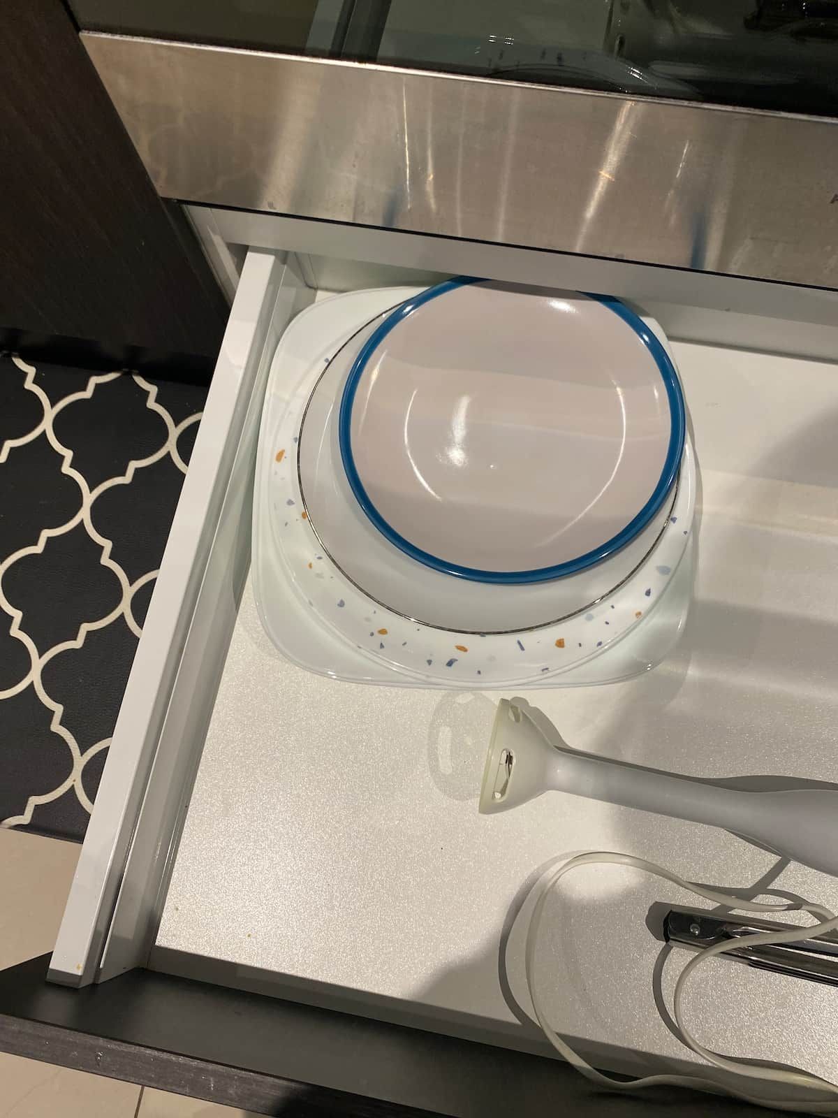 Una cocina con extractor de acero inoxidable, encimera blanca y salpicadero con diseño.