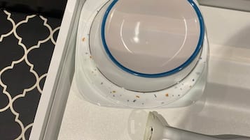 Una cocina con extractor de acero inoxidable, encimera blanca y salpicadero con diseño.