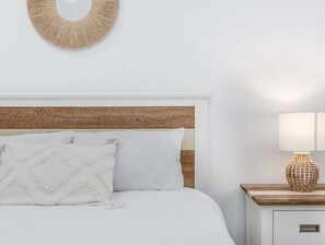 Ein Bett mit Holz-Kopfteil, weißer Bettwäsche und einer Wanddekoration darüber.