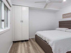 Un dormitorio con una cama, un armario y un ventilador de techo.