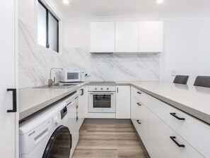 Eine kleine Küche mit Waschmaschine, Mikrowelle und Backofen.