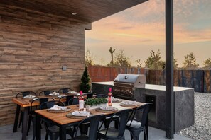 An outdoor dining area with a wooden table set for six, a grill, and a view of the sky. - JT luxe Compound Pool, Spa, Floodlit Pickleball, Sauna, Dome (Joshua Tree)