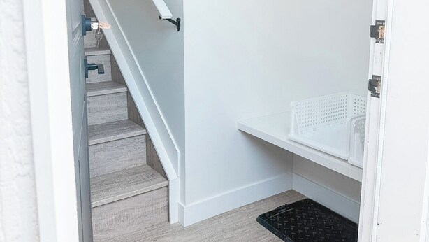 A staircase leading to a closet with a white door, a hanging rack, and a black rug. - Serene 1-bedroom apartment in Edmonton (Edmonton)