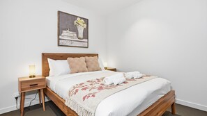 A neatly made bed with a floral throw, two bedside lamps, and a framed picture above. - The Rose Above the City Melbourne CBD (Melbourne)