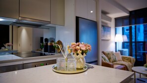 Une cuisine moderne avec un plan de travail en marbre, un vase rempli de fleurs et un plateau contenant de la verrerie.