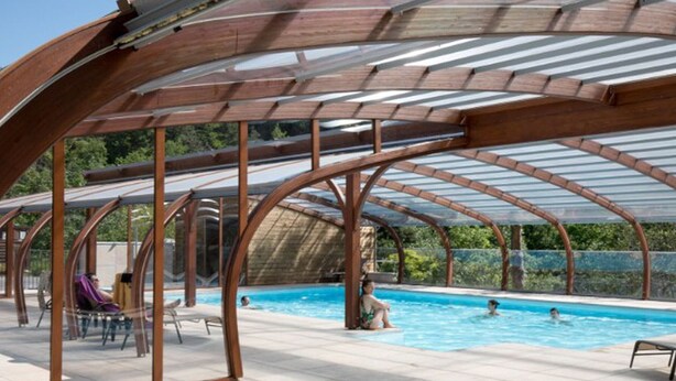 An outdoor swimming pool with a covered area, clear skies, and a person swimming. - Cozy roulotte, pets welcome - 4 guests (Saint-Paulien)