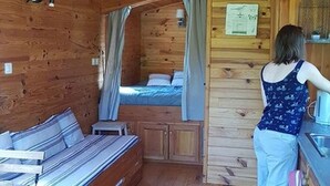 A cabin interior with a bed, a small kitchenette, and a bathroom. - Cozy roulotte, pets welcome - 4 guests (Saint-Paulien)