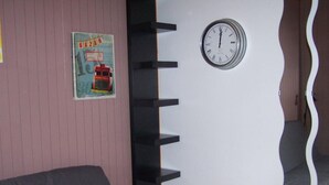 Et værelse med et ur på væggen, et billede og et unikt, buet designelement.