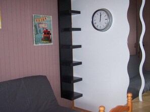 Ein Zimmer mit einer Uhr an der Wand, einem Poster und einem einzigartigen, geschwungenen Designelement.