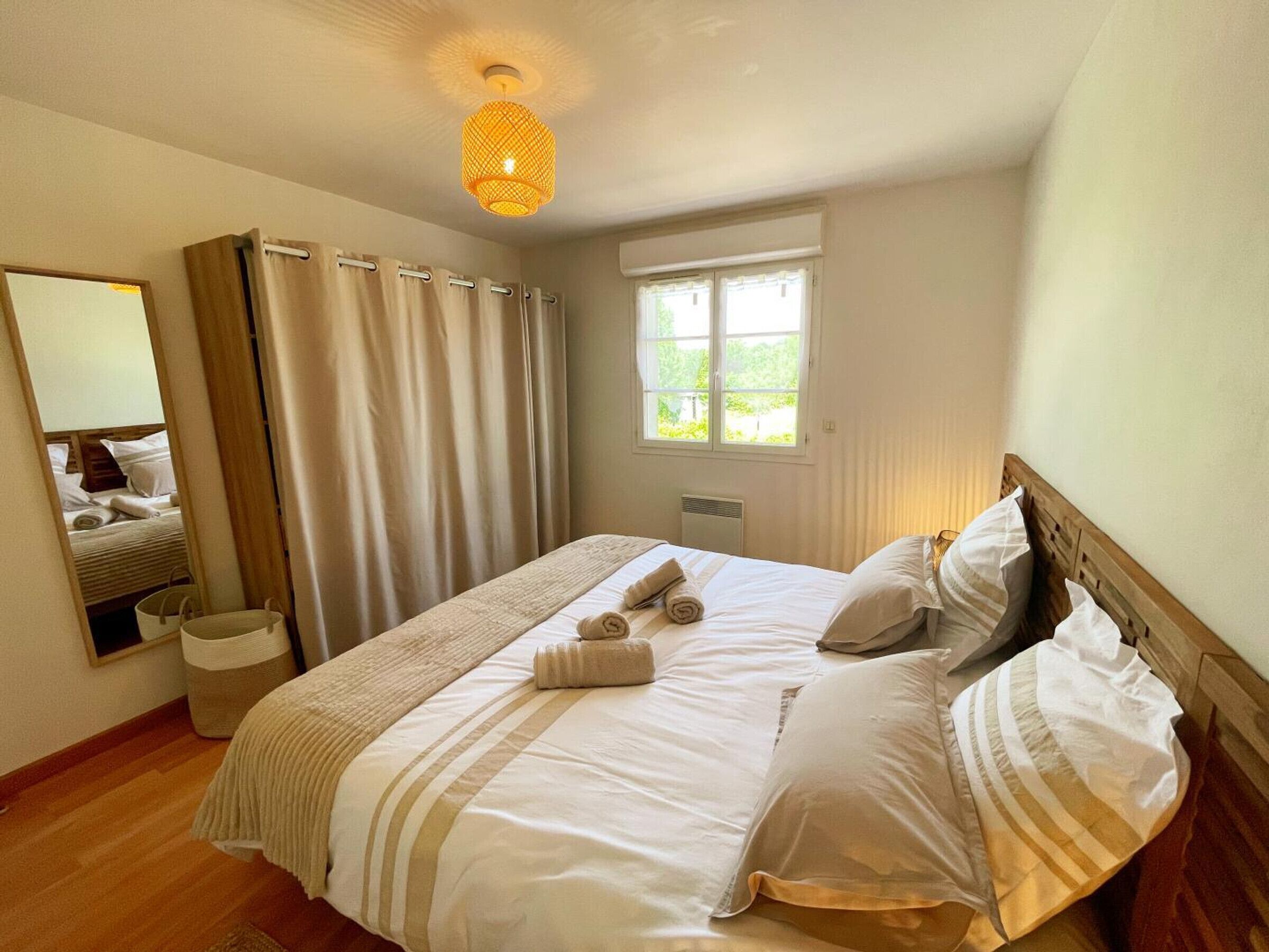Quarto com cama, janela, espelho e luminária no teto.
