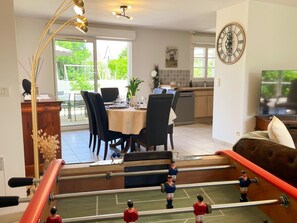 A dining area with a table set for four, a kitchen in the background, and a sports table below. - Single-story house in Chenonceaux - 6 guests (Chenonceaux)