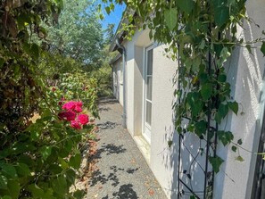 A narrow pathway flanked by lush greenery and a building with a white exterior. - Single-story house in Chenonceaux - 6 guests (Chenonceaux)