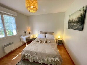 A bedroom with a bed, bedside tables, a desk, a chair, a window, and a wall-mounted picture. - Single-story house in Chenonceaux - 6 guests (Chenonceaux)