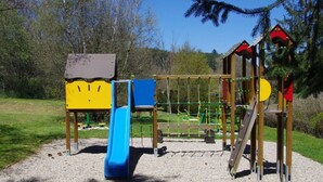 Ein Spielplatz mit Rutsche, Klettergerüsten und einer kleinen Schutzhütte.