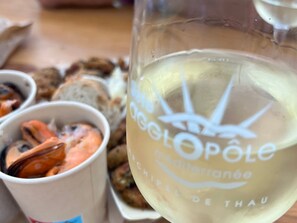 Ein Glas mit dem Aufdruck 'La Cote d'Or' und 'Château de Thau', eine Schüssel mit Essen und eine Brotdose.