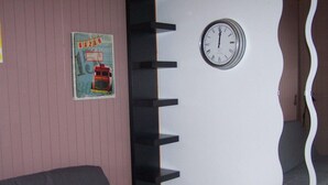 Una stanza con un letto, una sveglia a parete e un quadro.