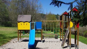 Un'area giochi con uno scivolo, strutture per arrampicarsi e un piccolo riparo.