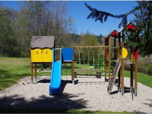 Ein Spielplatz mit Rutsche, Klettergerüsten und einer kleinen Schutzhütte.