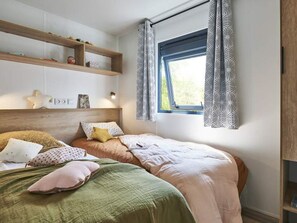 A bedroom with a bed, pillows, a headboard, a window, and a shelf with items. - Family mobile home, pets welcome - 6 guests (Saint-Paulien)