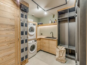 Eine kleine Küche mit Waschmaschine, Spüle und einem Edelstahl-Kühlschrank.