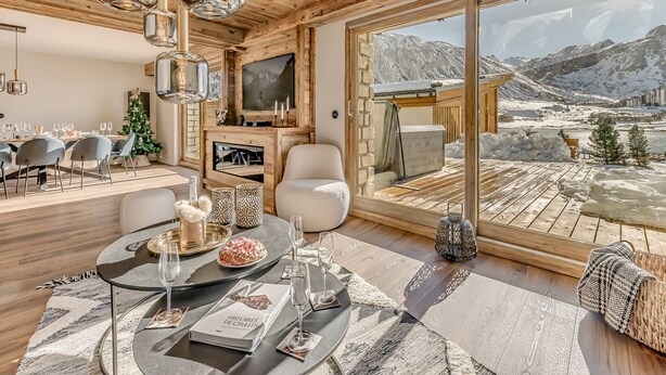 A modern interior with a dining area, a fireplace, and a large window offering a mountain view. - Spacious apartment, lake view - 14 guests (Tignes)