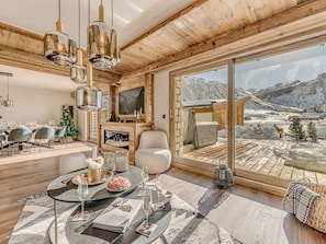 A modern interior with a dining area, a fireplace, and a large window offering a mountain view.