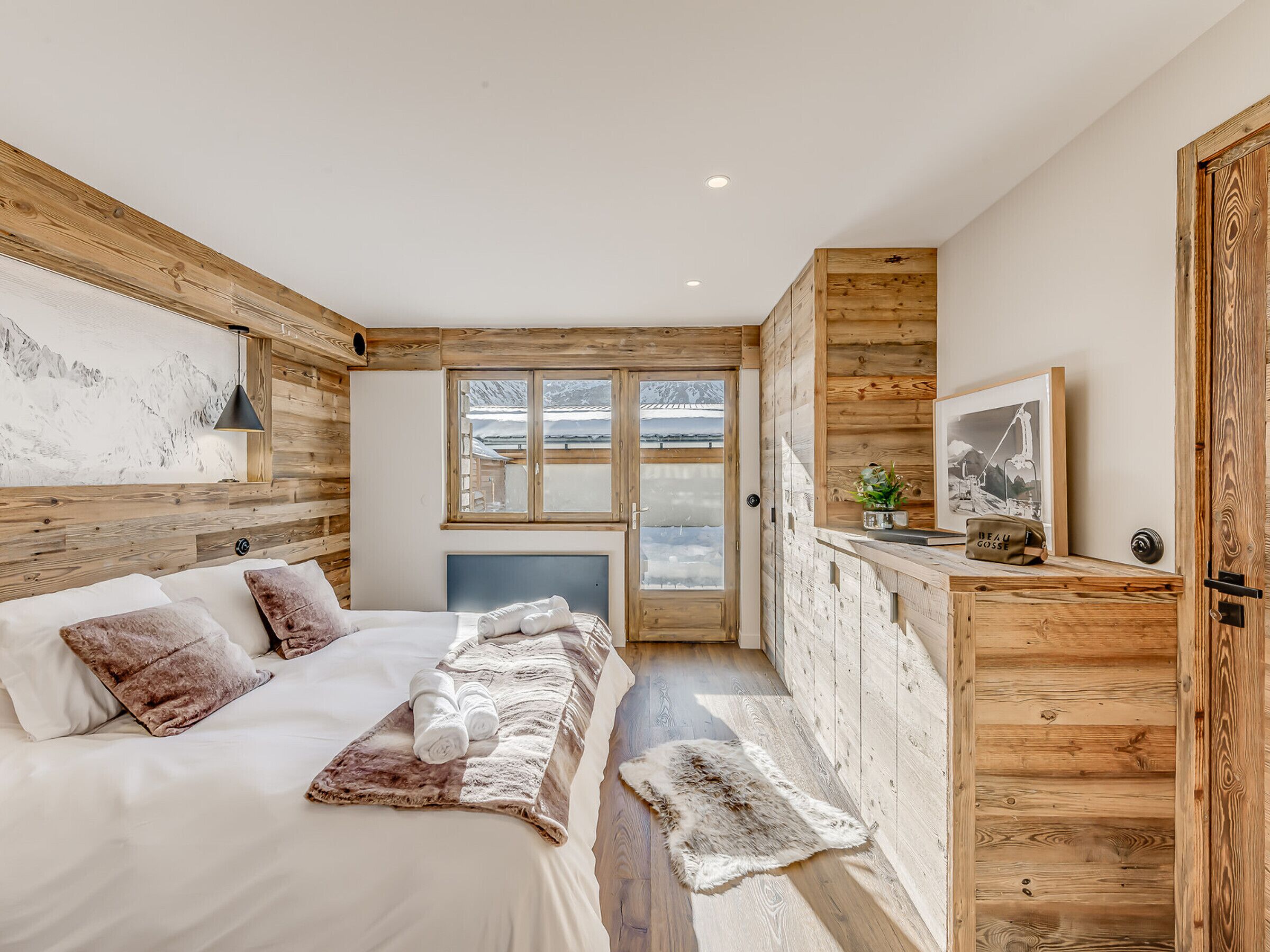 Un dormitorio con cama, paredes de madera, ventana y puerta.