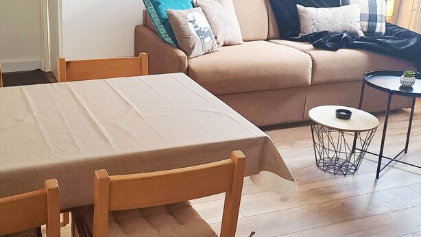 A living room with a sofa, a dining table, and a small round table with a lamp. - Functional apartment in the heart of Tignes - 4 guests (Tignes)