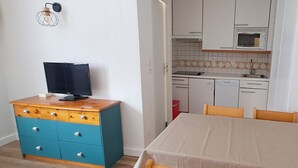 A compact kitchen with white cabinets, a microwave, and a sink. There's a wooden table with chairs and a blue dresser with drawers. - Functional apartment in the heart of Tignes - 4 guests (Tignes)