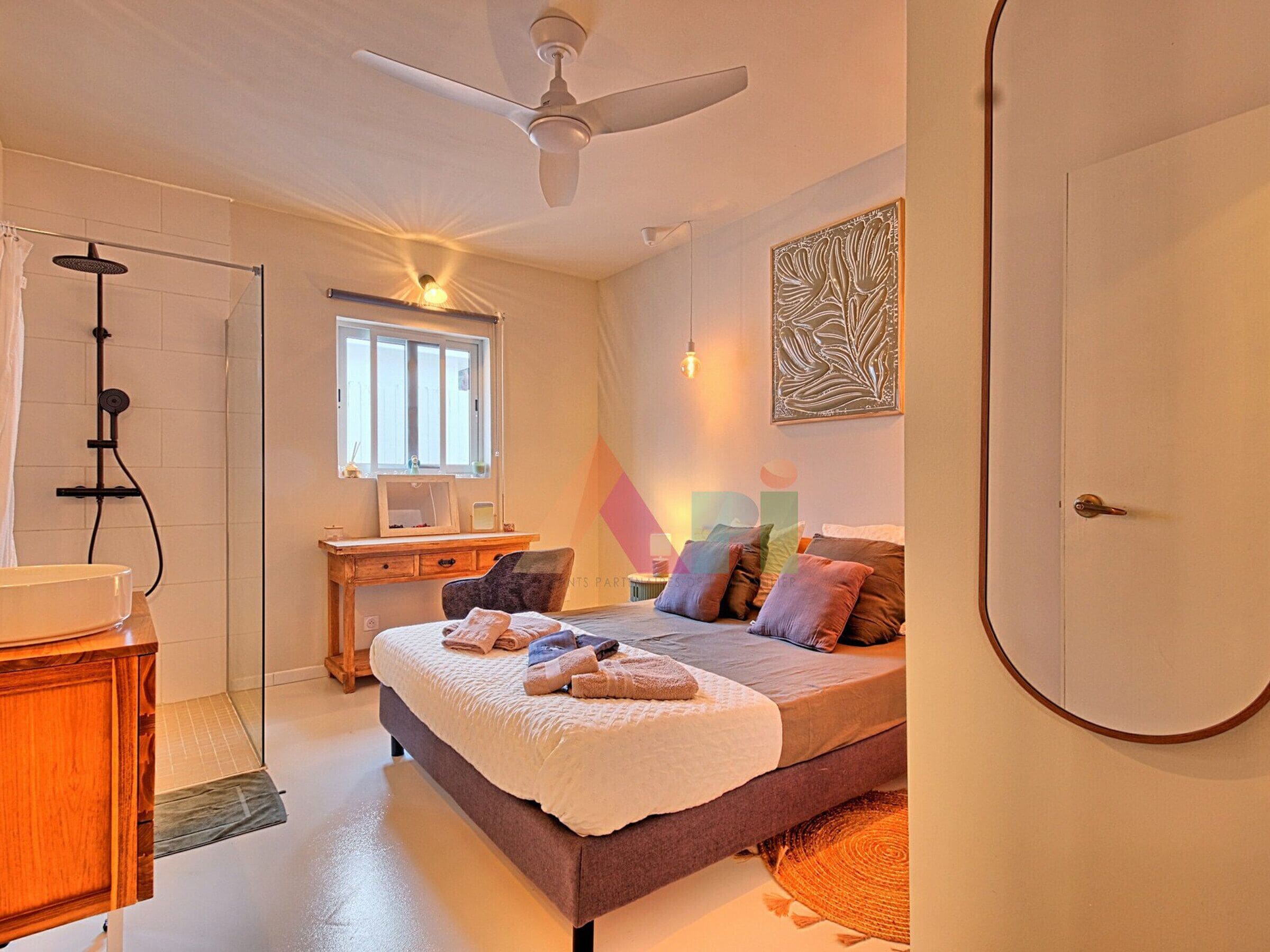 Ein Schlafzimmer mit einem Bett, einem Schreibtisch, einer Dusche und einem Deckenventilator.
