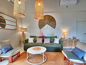 A living room with a green sofa, two armchairs, a coffee table, and decorative lamps.