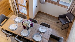 Ein Essbereich mit einem Holztisch, gedeckt für sechs Personen, umgeben von Stühlen, und einer Blumenvase auf dem Tisch.