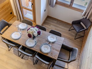 A dining area with a wooden table set for six, surrounded by chairs, and a vase of flowers on the table. - Charming duplex in the heart of Belle Plagne - 8 guests (Belle Plagne)