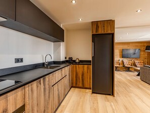 A modern kitchen with a wooden accent wall, a built-in oven, and a large refrigerator. - Charming duplex in the heart of Belle Plagne - 8 guests (Belle Plagne)