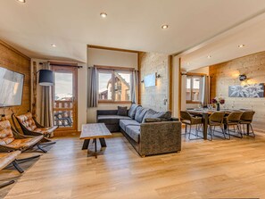 A modern living room with a sofa, chairs, a dining table, and a TV. - Charming duplex in the heart of Belle Plagne - 8 guests (Belle Plagne)