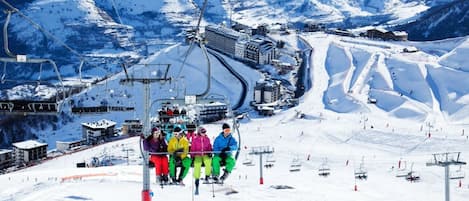 A ski lift with passengers, a snow-covered mountain landscape, and a ski resort infrastructure.