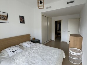 Ein Schlafzimmer mit Bett, Nachttisch, Schrank und einer Tür zu einem weiteren Raum.