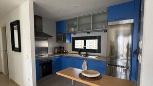 Une cuisine moderne avec des armoires bleues, des appareils en acier inoxydable et une table en bois.