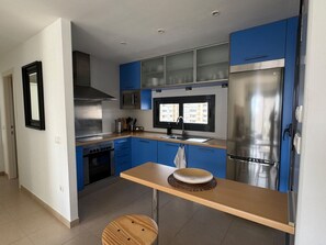 Eine moderne Küche mit blauen Schränken, Edelstahlgeräten und einem Holztisch.