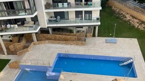 Un immeuble résidentiel à plusieurs étages doté d’une piscine et d’espaces extérieurs aménagés pour se détendre.