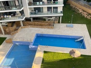 Ein mehrstöckiges Wohngebäude mit Schwimmbad und Außenbereich mit Sitzgelegenheiten.
