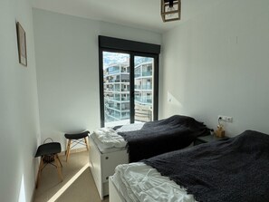 A bedroom with two beds, a small desk, a chair, and a window with a city view. - Mediterranean comfort apartment - 4 guests (Villajoyosa)