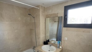 Une salle de bain avec une baignoire, un lavabo, un miroir et une fenêtre.